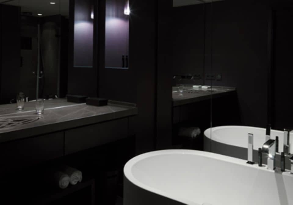 Auch im Bad wurde auf dunkle Farben gesetzt und dazu eine weiße freistehende Badewanne kombiniert.