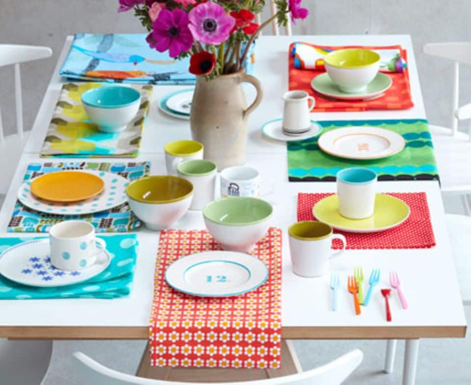 Schnelle Tischdeko mit bunten Tischsets: Einfach Stoff- oder Tapetenreste mit Hilfe von Schere und Nähmaschine auf die gewünschte Größe bringen und unter den Tellern drapieren.