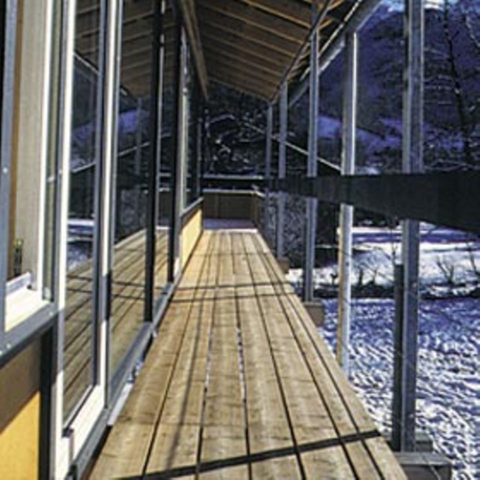 Aschau/Chiemgau: Zum Garten und zur Kulisse der Kampenwand öffnen sich Fenster entlang einer Galerie in einfacher Konstruktion.
