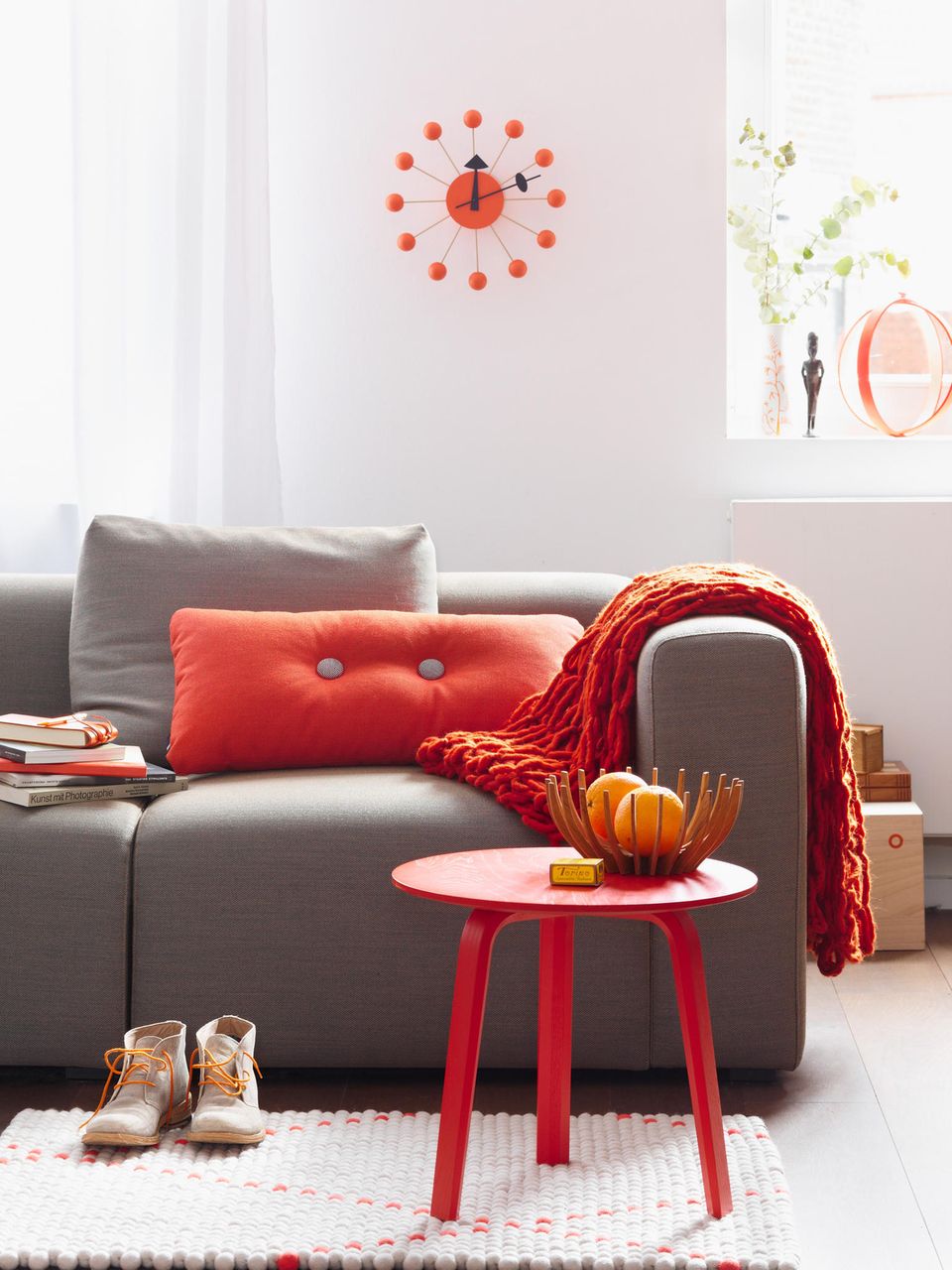Gemütliches Sofa in Grau mit Kissen und Beistelltisch in Rot