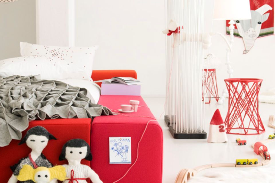 Spielzeug vor rotem Bett im Kinderzimmer