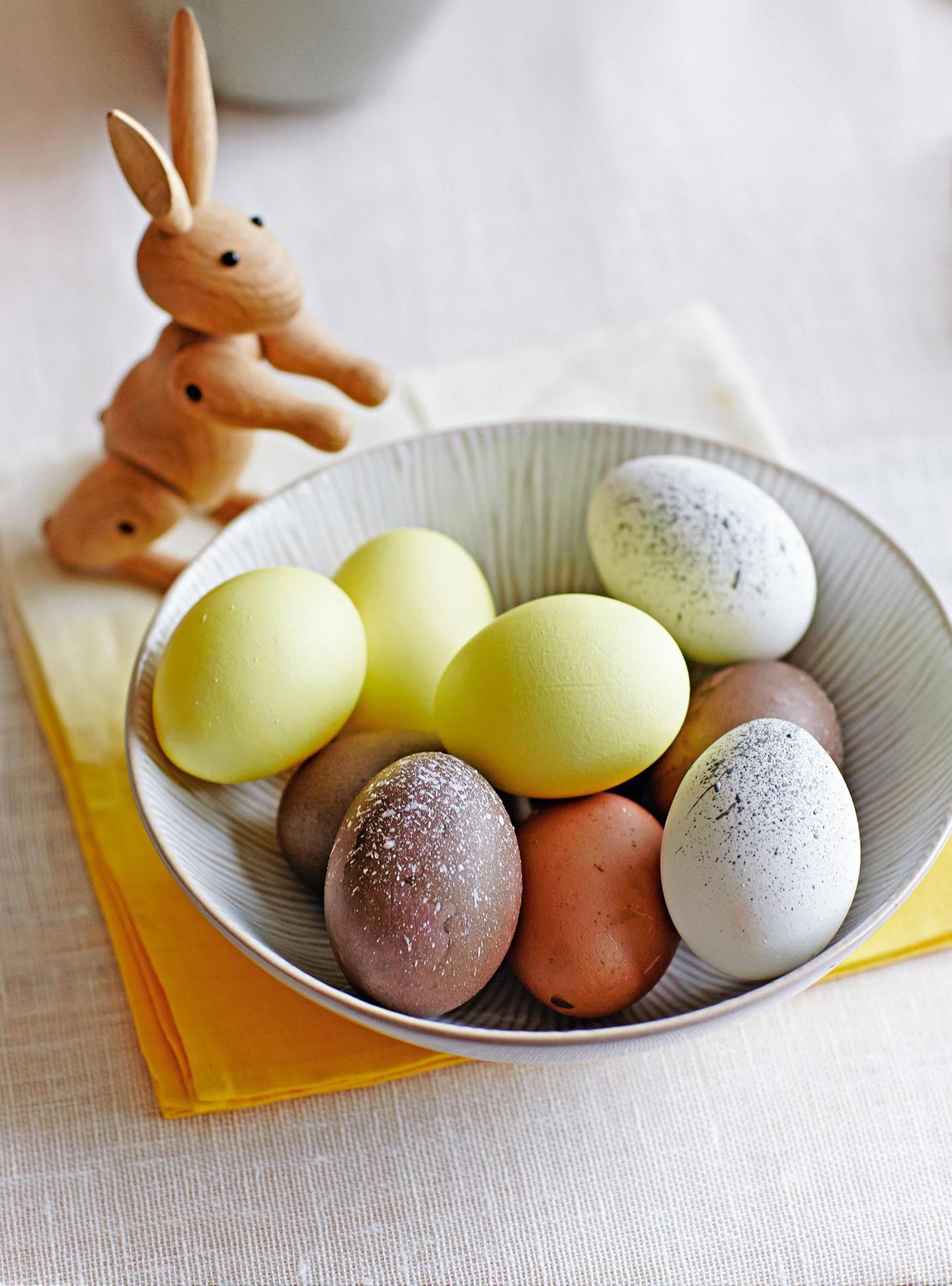 Gelb eingefärbte Eier und naturbelassene Eier in einer Schüssel