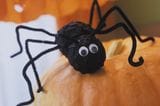 Schwarze Spinne als Halloweendeko auf einem Kürbis