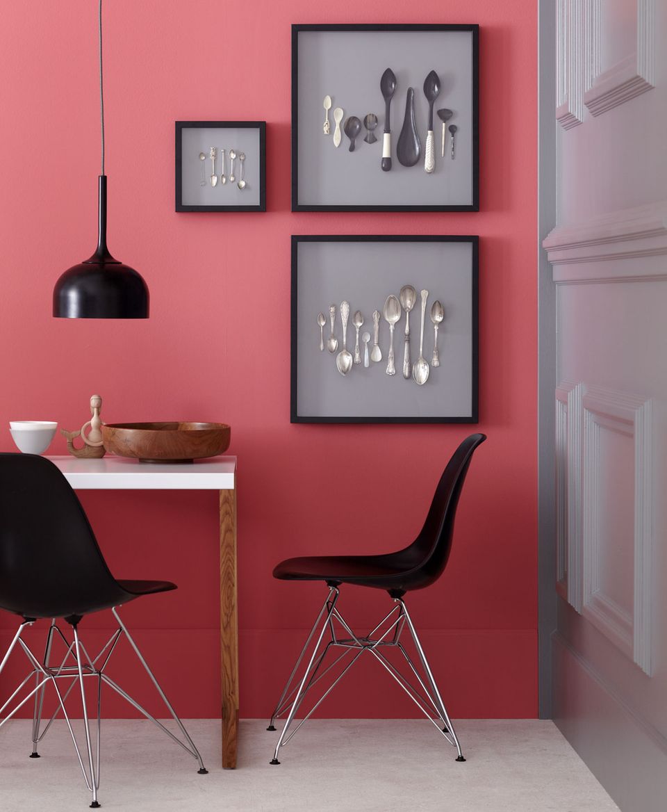 Möbelklassiker, Esstisch und Bilder vor einer Wand in Rot