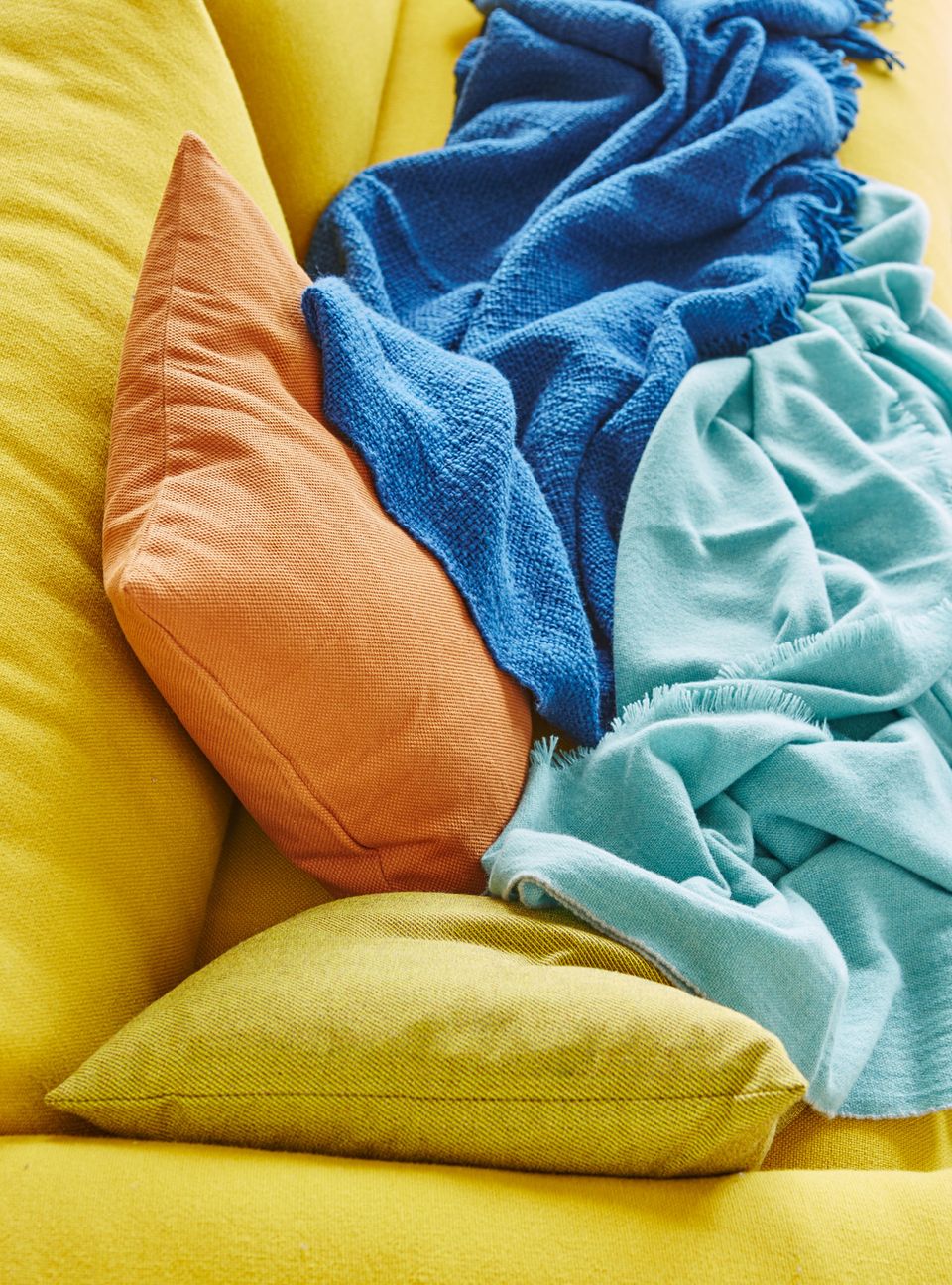 Kissen in Gelb und Orange sowie Decken in Balu und Türkis