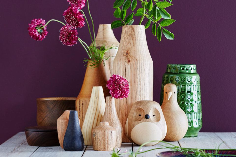 Vasen und Figuren aus Holz vor einer Wand in Lila