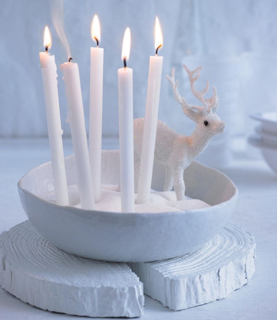 Winterliche Schneedeko mit Kerzen und einem Glitzerhirsch
