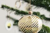 Weihnachtskugel aus Papier mit goldenen Streifen und Holzperlen