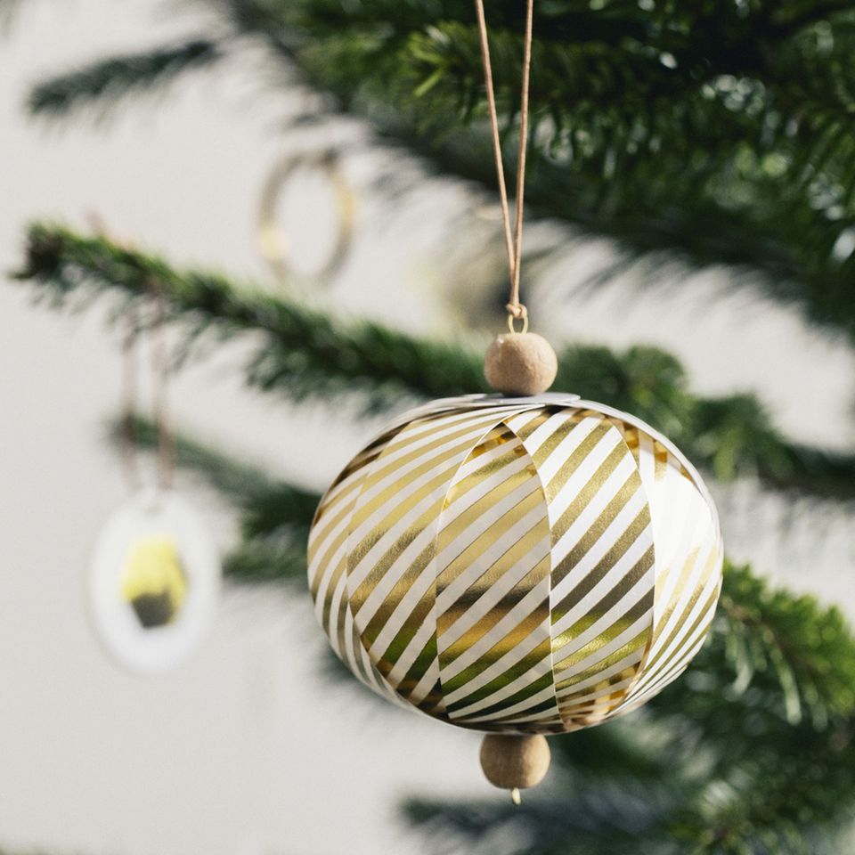 Weihnachtskugel aus Papier mit goldenen Streifen und Holzperlen