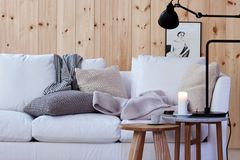 Sofa in Weiß, Wandvertäfelung aus Holz, Beistelltische aus Holz und gestrickte Kissenhüllen