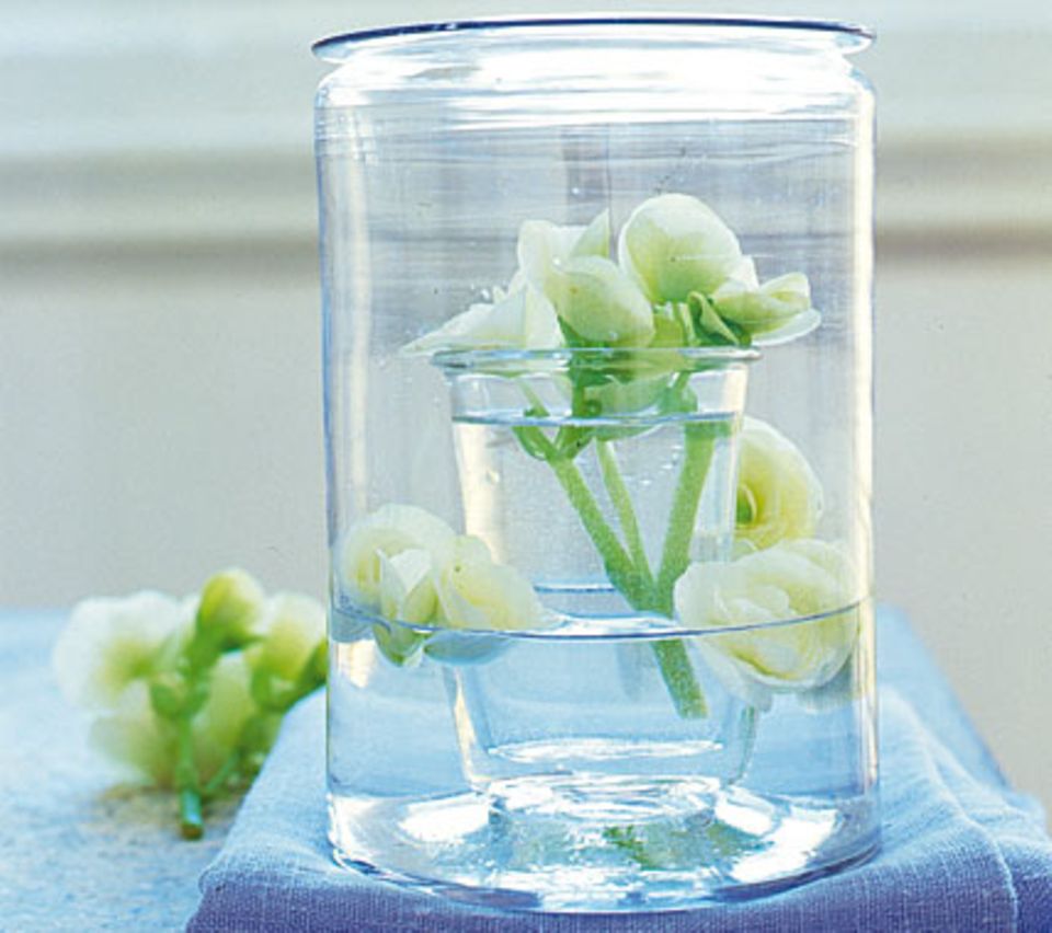 Kein teures Designstück, sondern selbst gemacht! Ein kleines Trinkglas in eine große Glasvase stellen und beide Gefäße mit Wasser und Blüten füllen. Foto: Anke Schütz