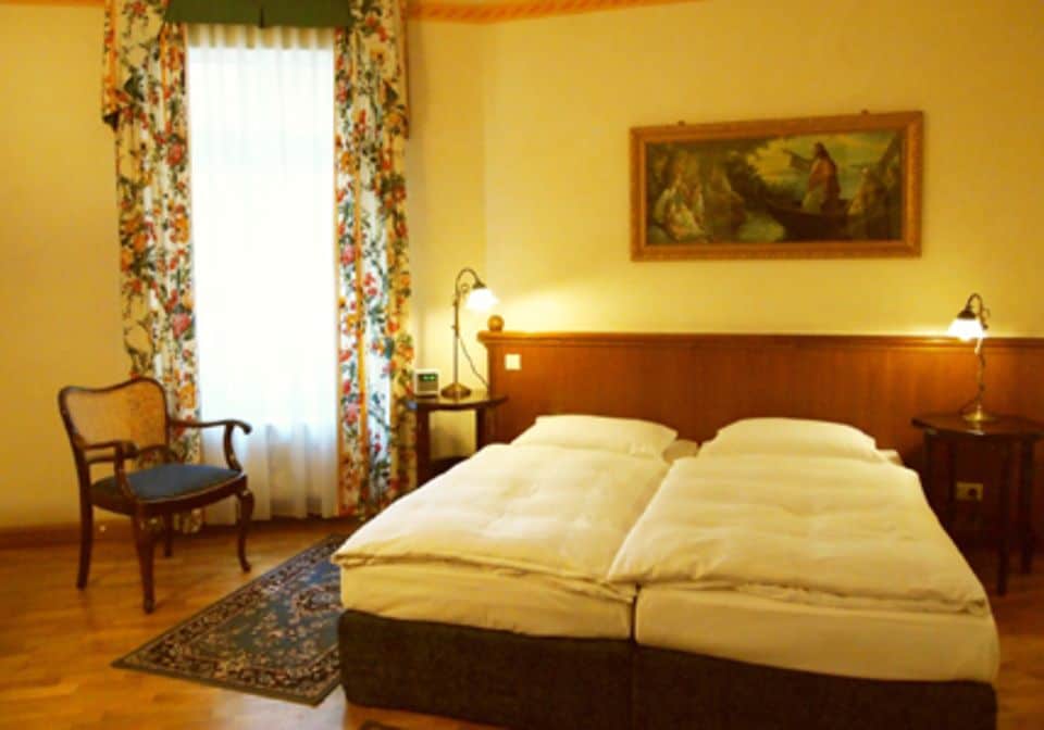 Vorhänge mit Blumenmuster, antike Holzmöbel und Ölbilder zieren die Hotelzimmer des Antikhotels.