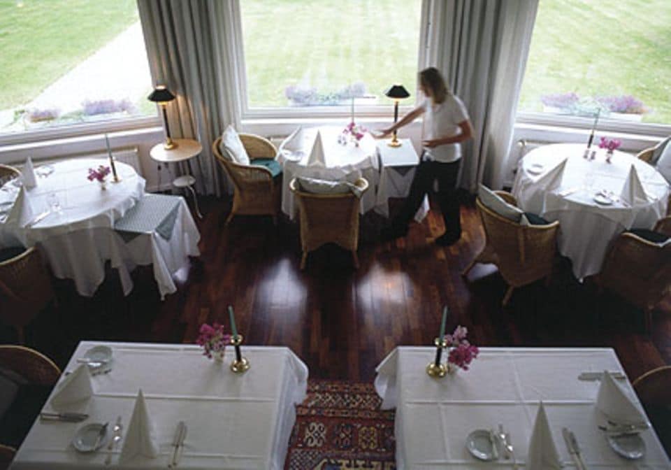 Dunkler Fußboden und weiß gedeckte Tische: der Gastraum im "Ich weiß ein Haus akm See".