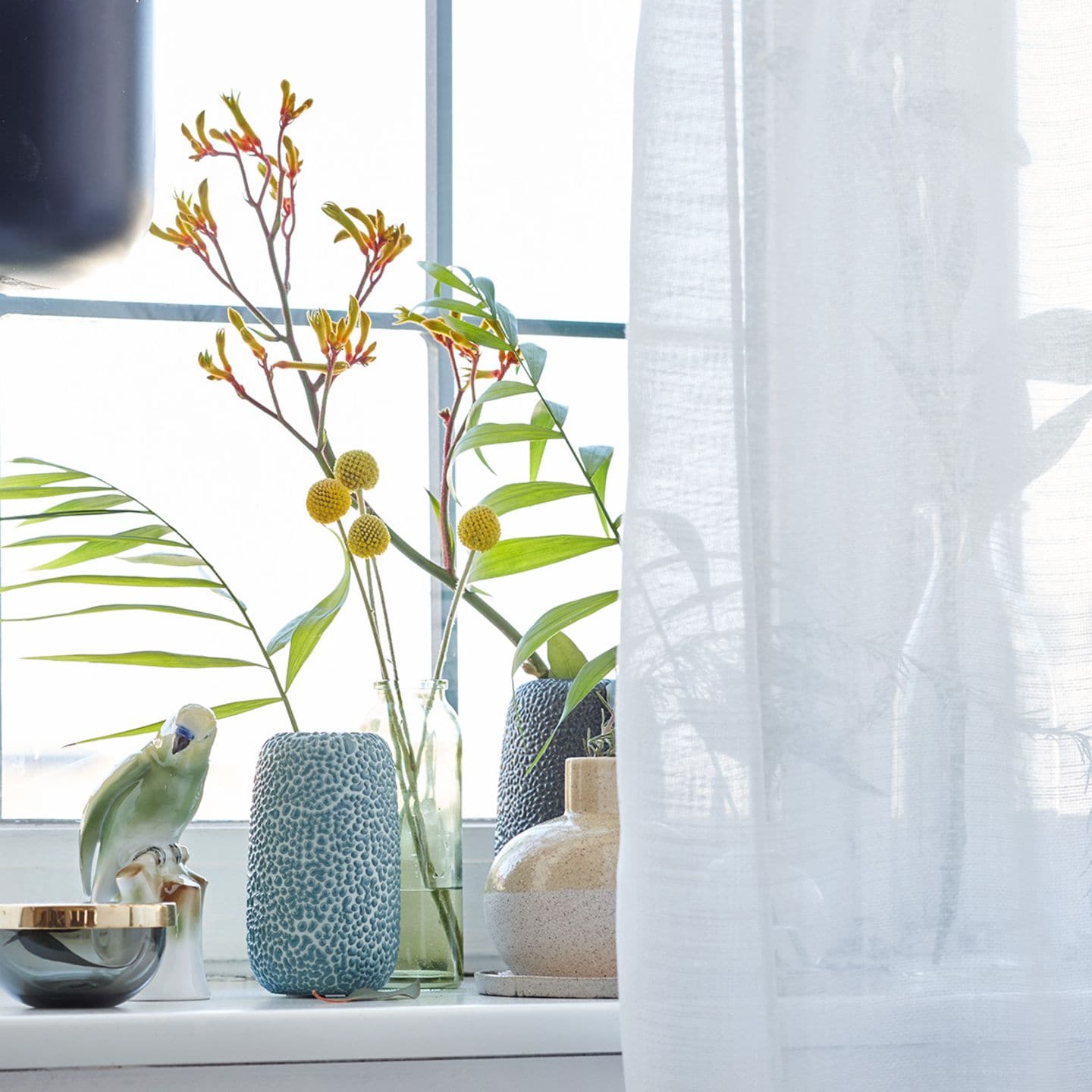Fensterbank mit unterschiedlichen Vasen dekorieren
