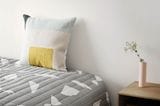 Kissen mit geometrischen Mustern auf Bett mit geometrischer Bettwäsche