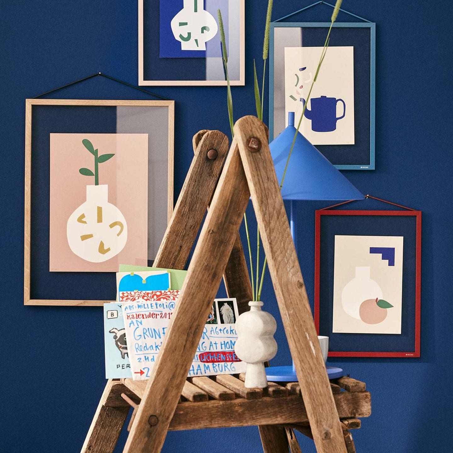 Blaue Wand mit Bildern und Leiter als Regal