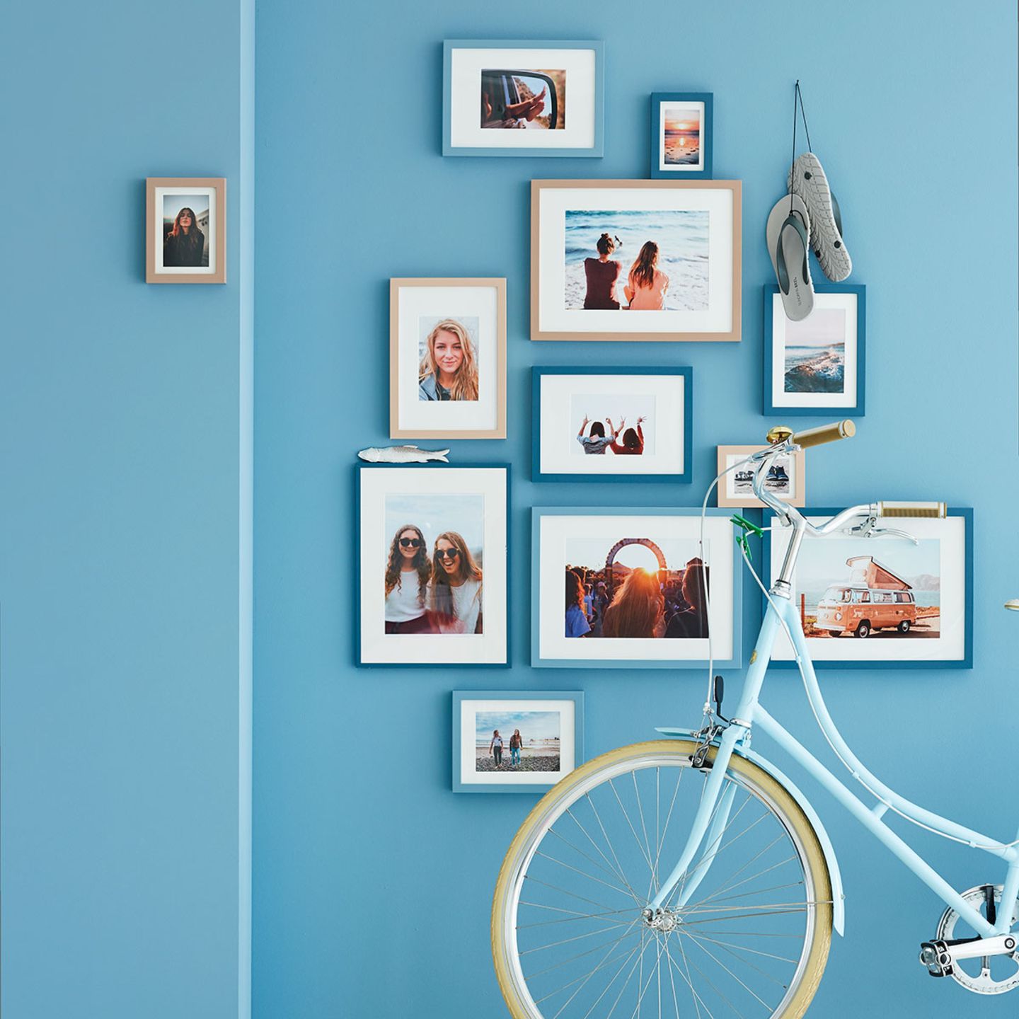 Fotos in verschieden großen Bilderrahmen sind spannend aufgehängt. Bilderrahmen und Wandfarbe harmonieren in verschiedenen Blau…