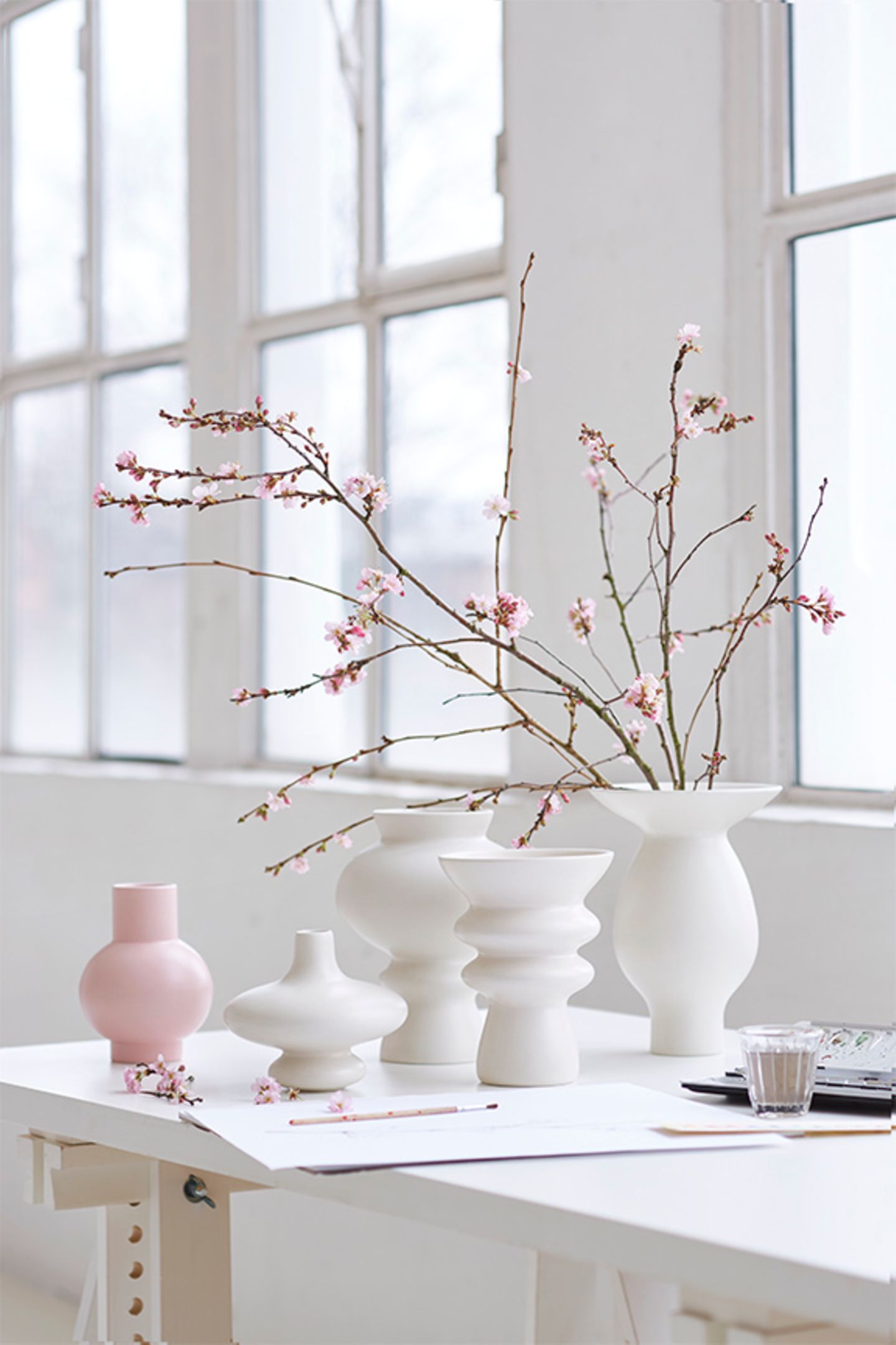 Rosa Kermikvase neben vier weißen Vasen