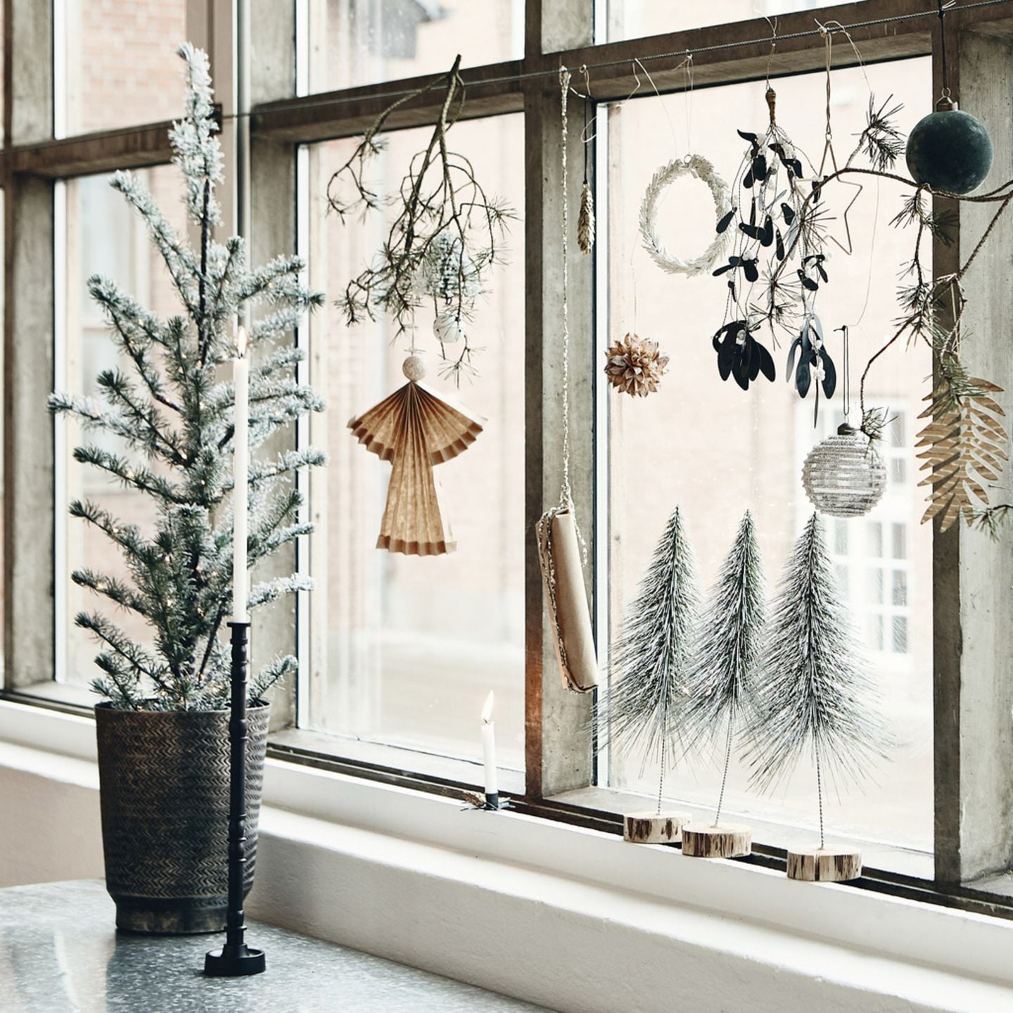 Weihnachtlich geschmücktes Fenster mit Ornamenten, getrockneten Zweigen, Christbaumkugeln und mehr