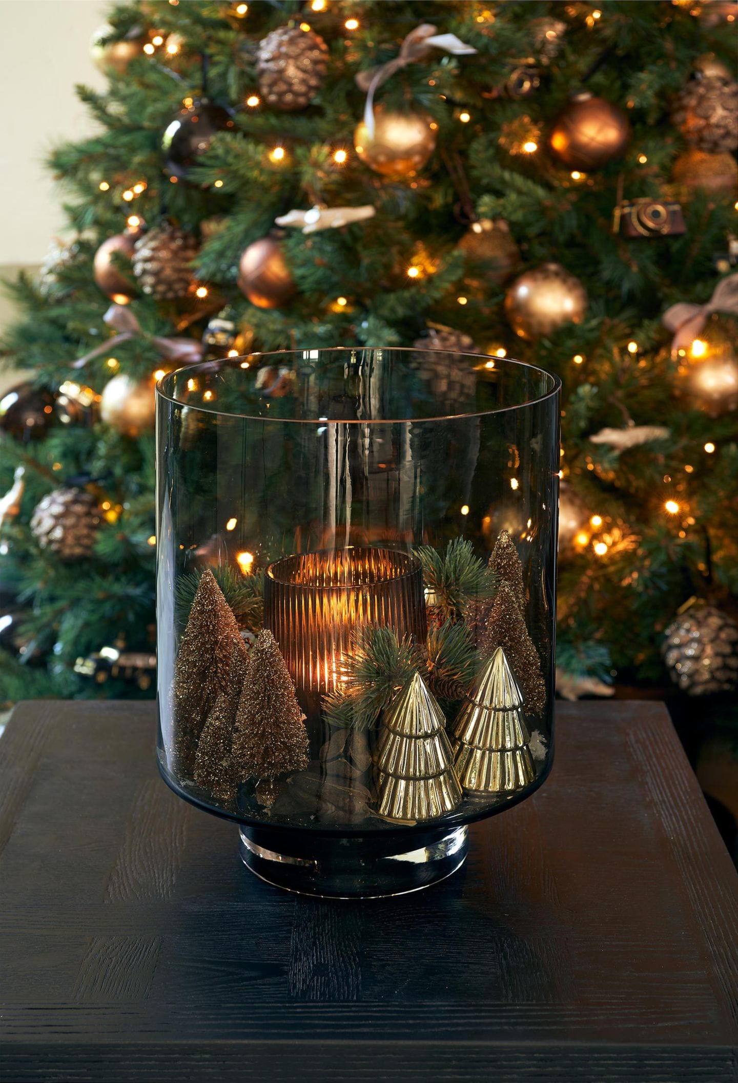Weihnachtlich dekoriertes Hurricane Glas vor einem geschmückten Weihnachtsbaum