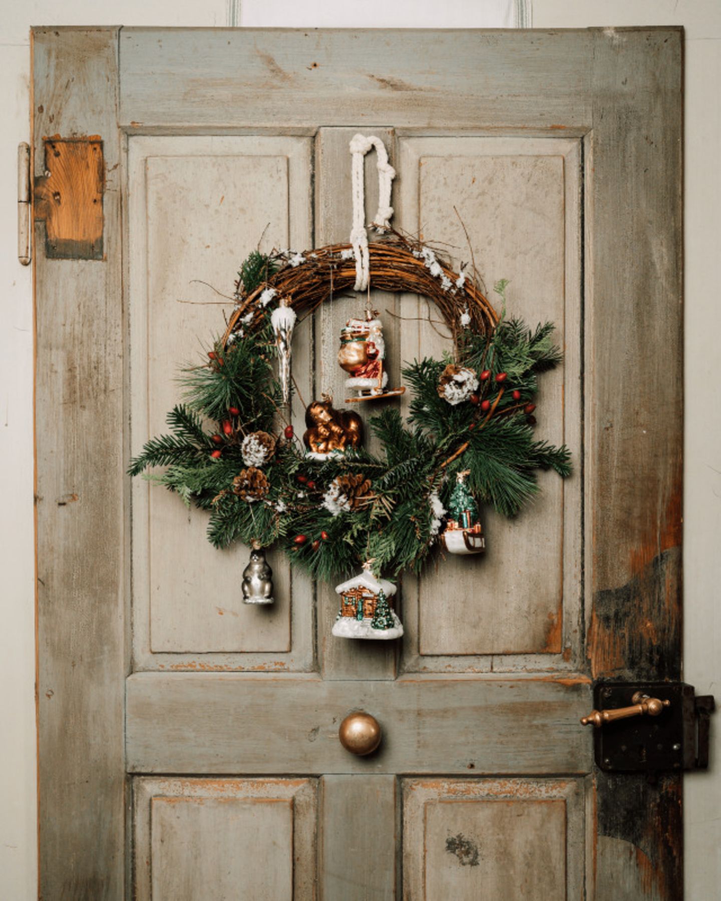 Türkranz mit Weihnachtsornamenten vor einer hellen Holztür