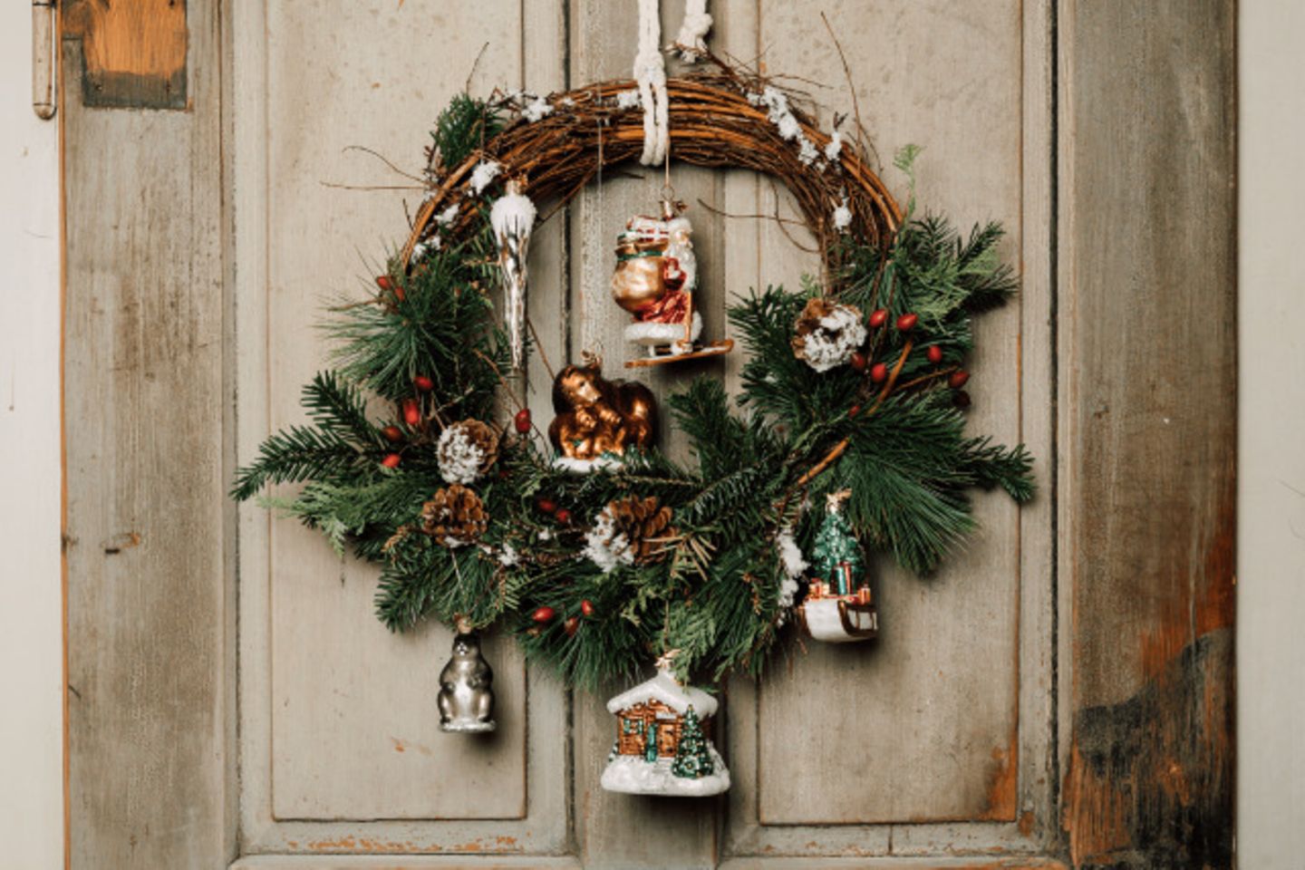 Türkranz mit Weihnachtsornamenten vor einer hellen Holztür