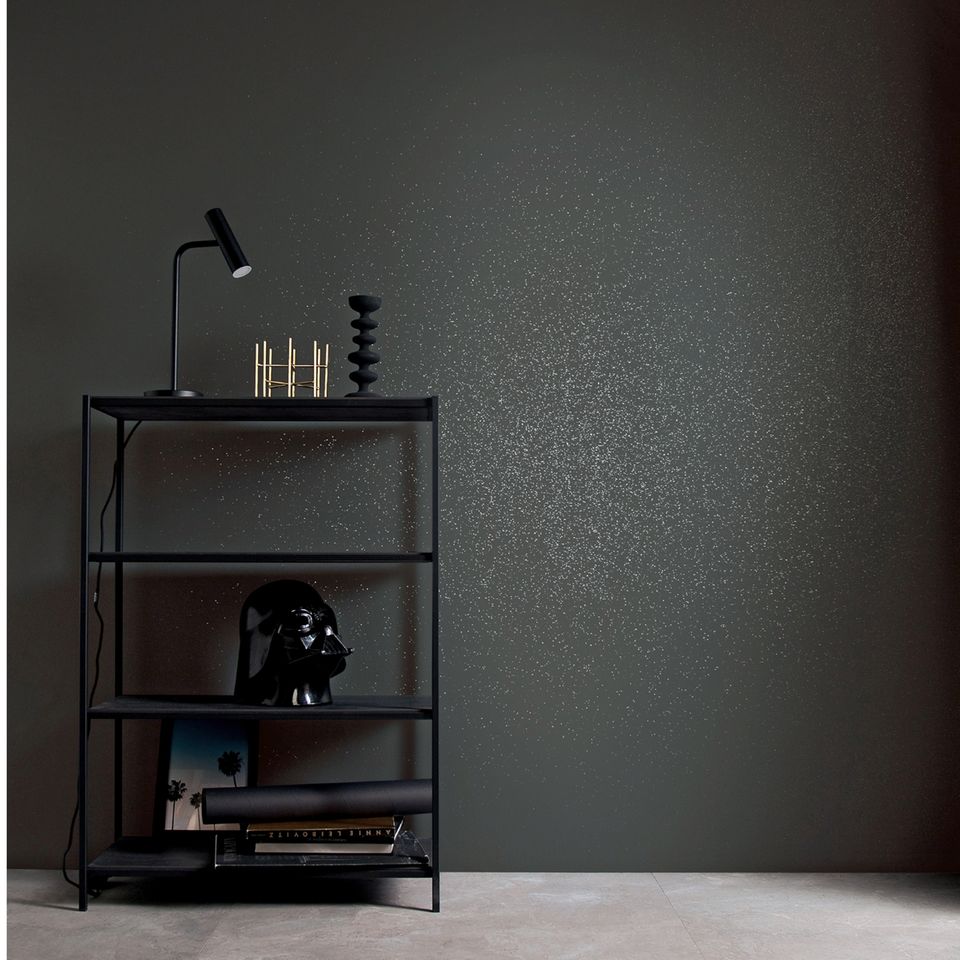 Grau-glitzernde Wand mit schwarzen Regal davor