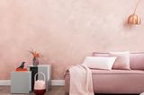 Wohnzimmer mit roségold-schimmernder Wandfarbe und Sofa in Rosa