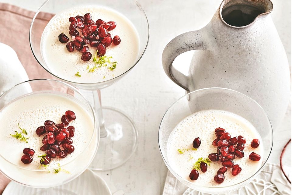 Weißes Pannacotta in Champagnergläsern auf einem weiß gedecktem Tisch