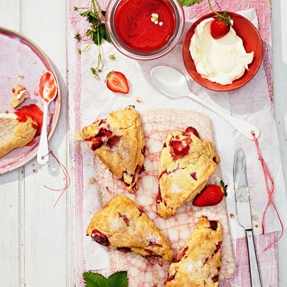 Unsere Variante des britischen Teatime-Klassikers „Scones with Clotted Cream and Strawberry Jam”: Statt lange eingekochter Konfitüre bereiten wir einen Blitzaufstrich zu, und der mürbe Teig wird durch frische Erdbeeren herrlich saftig. Creme double dazu – wunderbar!