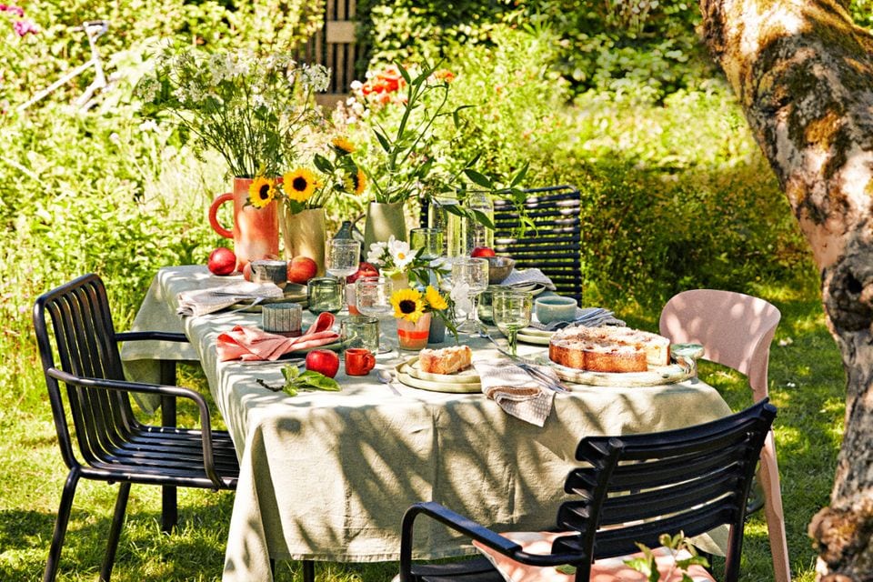 Spätsommerlich gedeckter Tisch im Garten mit Apfelkuchen und Sonnenblumen