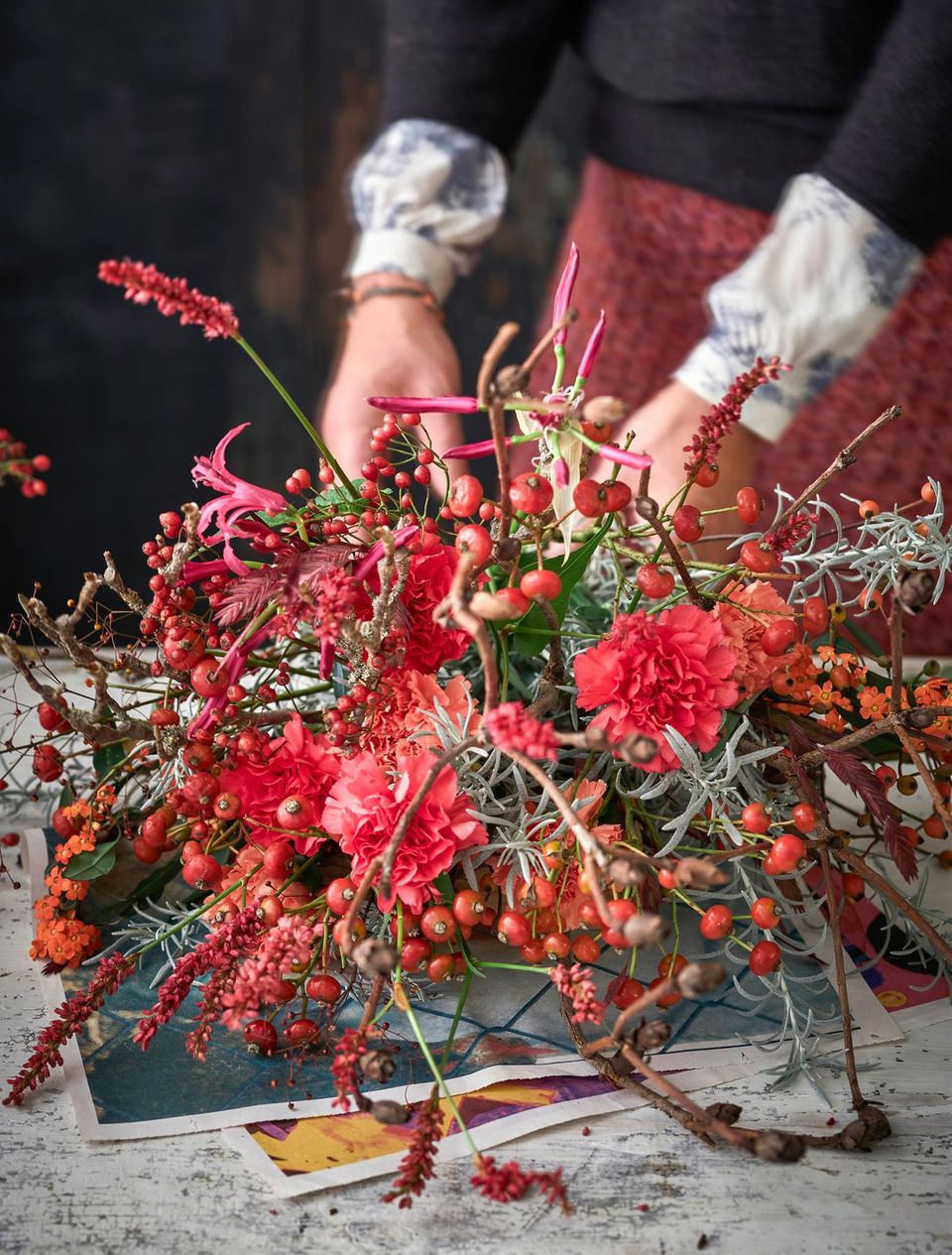 Ein roter Strauß aus Ästen, Beeren und Blüten wird zusammengebunden