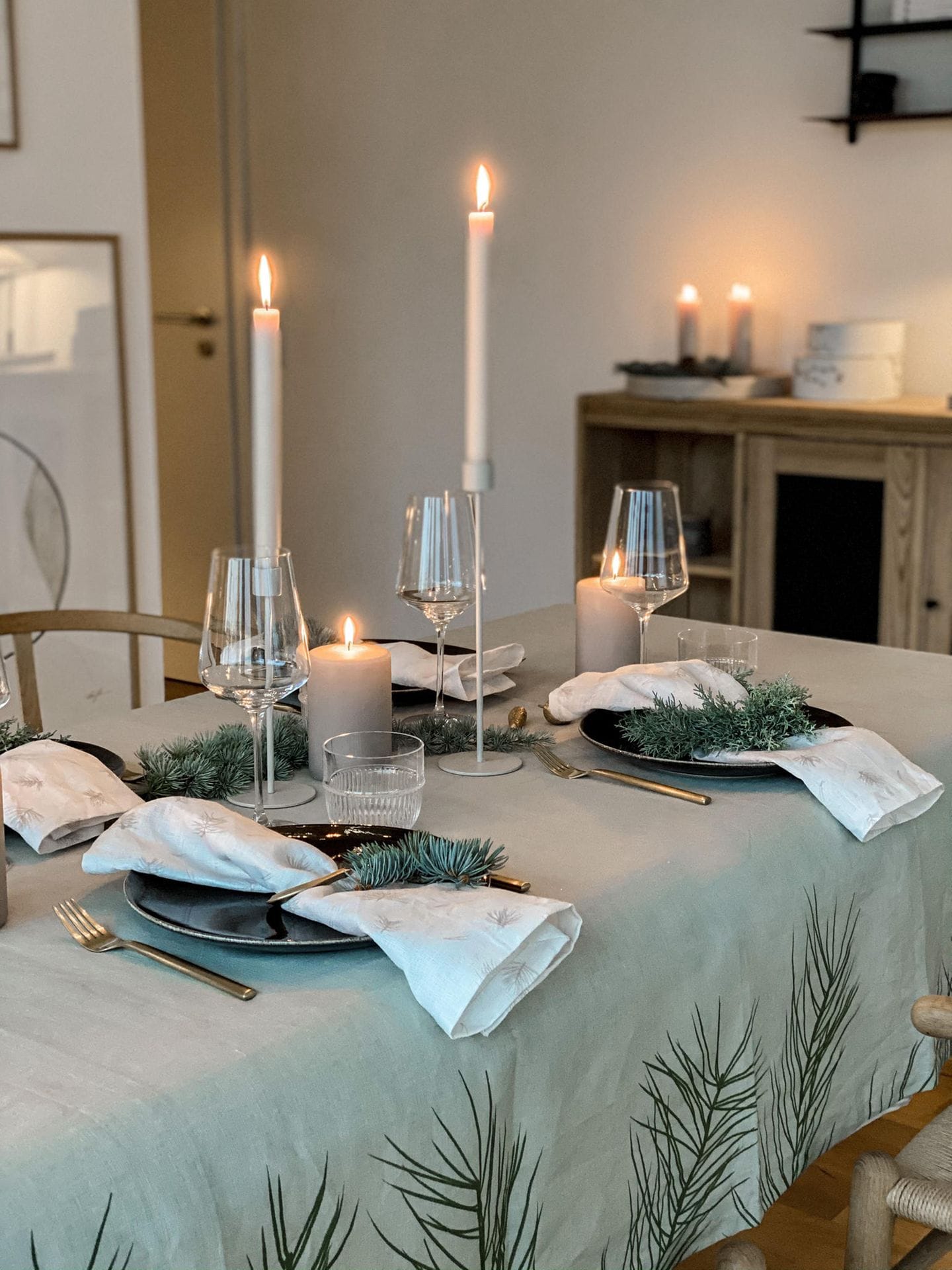 Tischdeko in grau mit grauer Musterdecke, dunkelblauen Tellern, goldenem Besteck und silbernen Kerzen