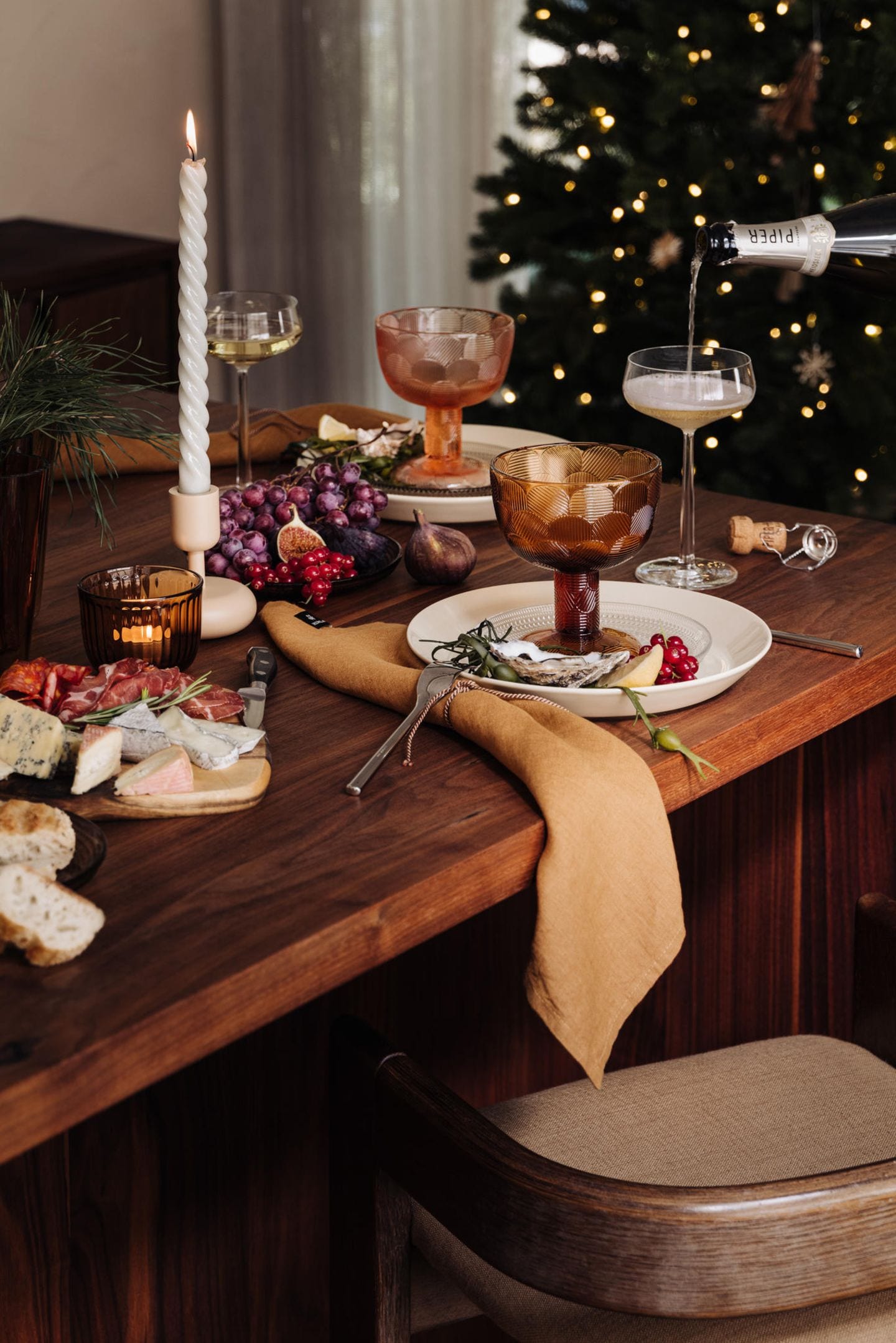 Rustikaler Weihnachtstisch mit Käsebrett und Trauben, erdfarbenem Geschirr und braunen Leinenservietten