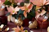 Kleines Tischgesteck mit pastellfarbenen Weihnachtssternen auf einer brombeerfarbenen Tischdecke