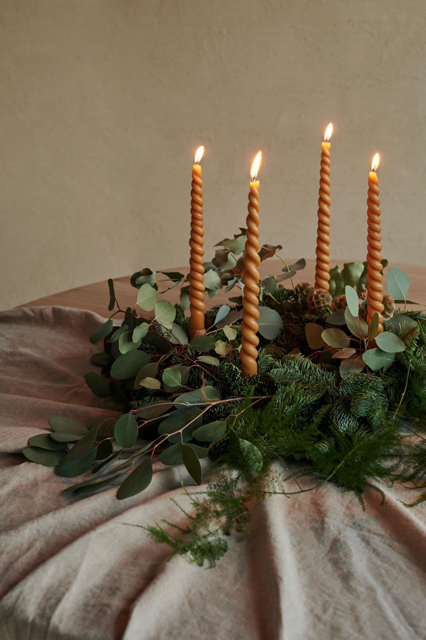 Adventskranz aus Tannengrün mit dekorativem Eukalyptus und gedrehten Kerzen