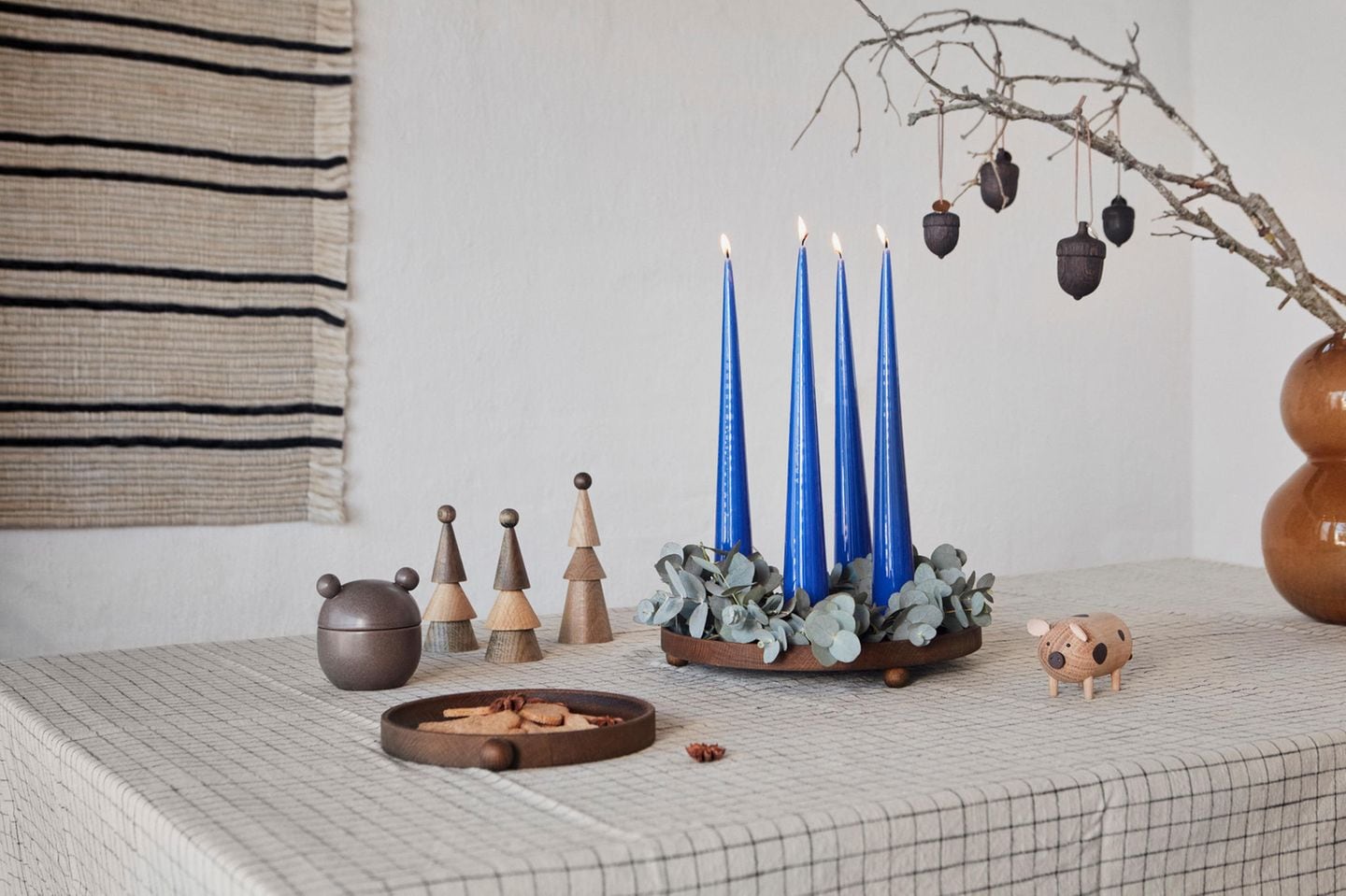 Auf einem Holztablett sind blaue Kerzen und Eukalyptus zu einem außergewöhnlichen Adventskranz arrangiert