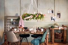 Über einem rustikalen Holztisch schwebt ein prachtvoller Adventskranz aus Tannengrün