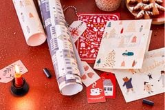Geschenkanhänger und Geschenkpapier für Weihnachtsgeschenke auf rotem Boden
