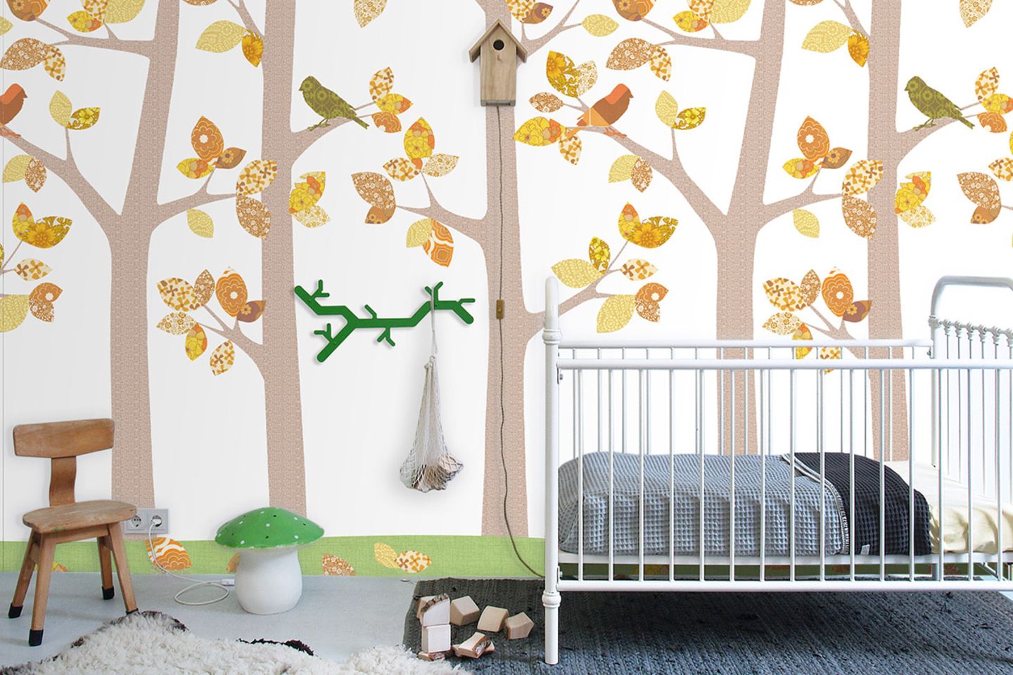 Frontaler Blick auf eine Kinderzimmerwand mit Waldtapete, Gitterbett und verschiedenen Kinderaccessoires davor