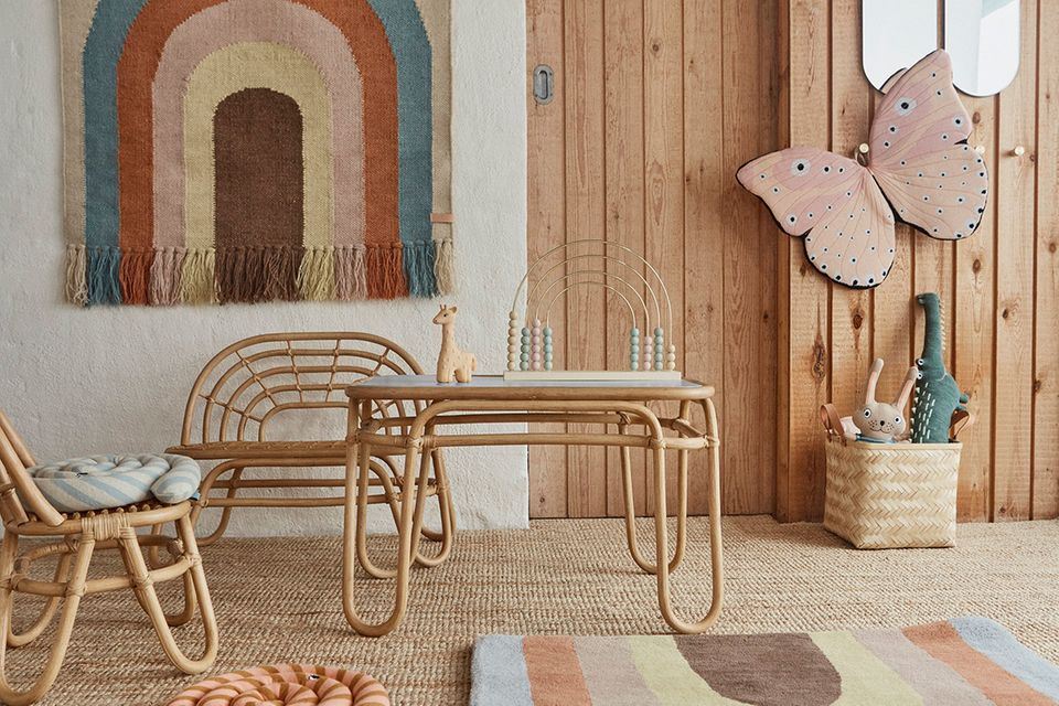 Stilvolles Kinderzimmer mit farbenfrohen Accessoires wie einem Wandteppich, Schmetterlingsflügeln