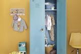 Hellblauer Kinderkleiderschrank vor gelber Wand