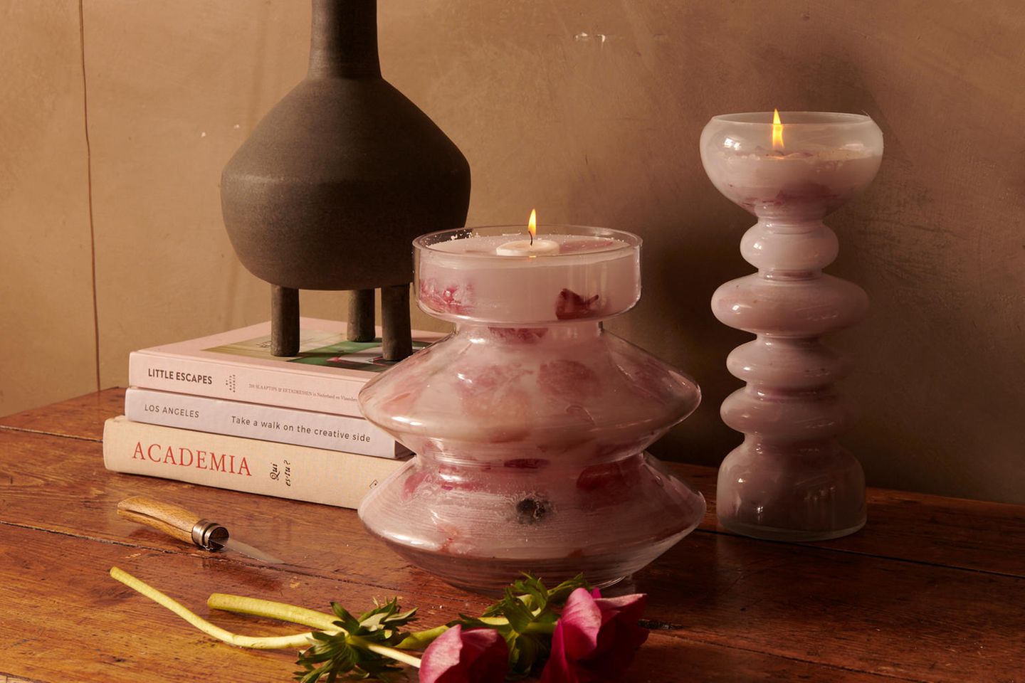 Selbstgemachte Duftkerzen in verschiedenen Größen und Formen mit Anemonen auf einem dunklen Holztisch