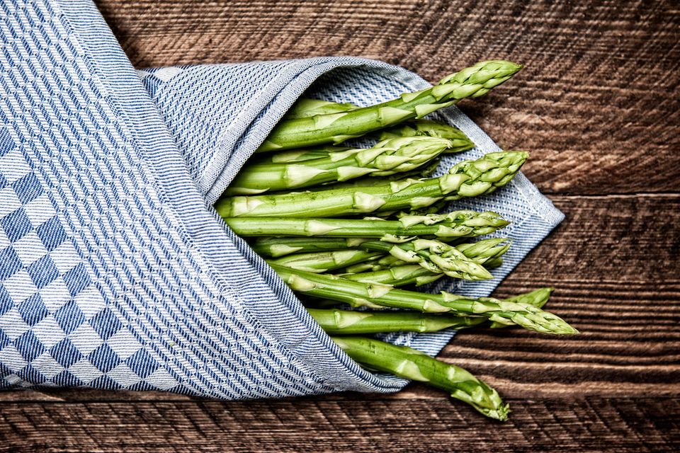 grüner spargel im handtuch auf Holztisch