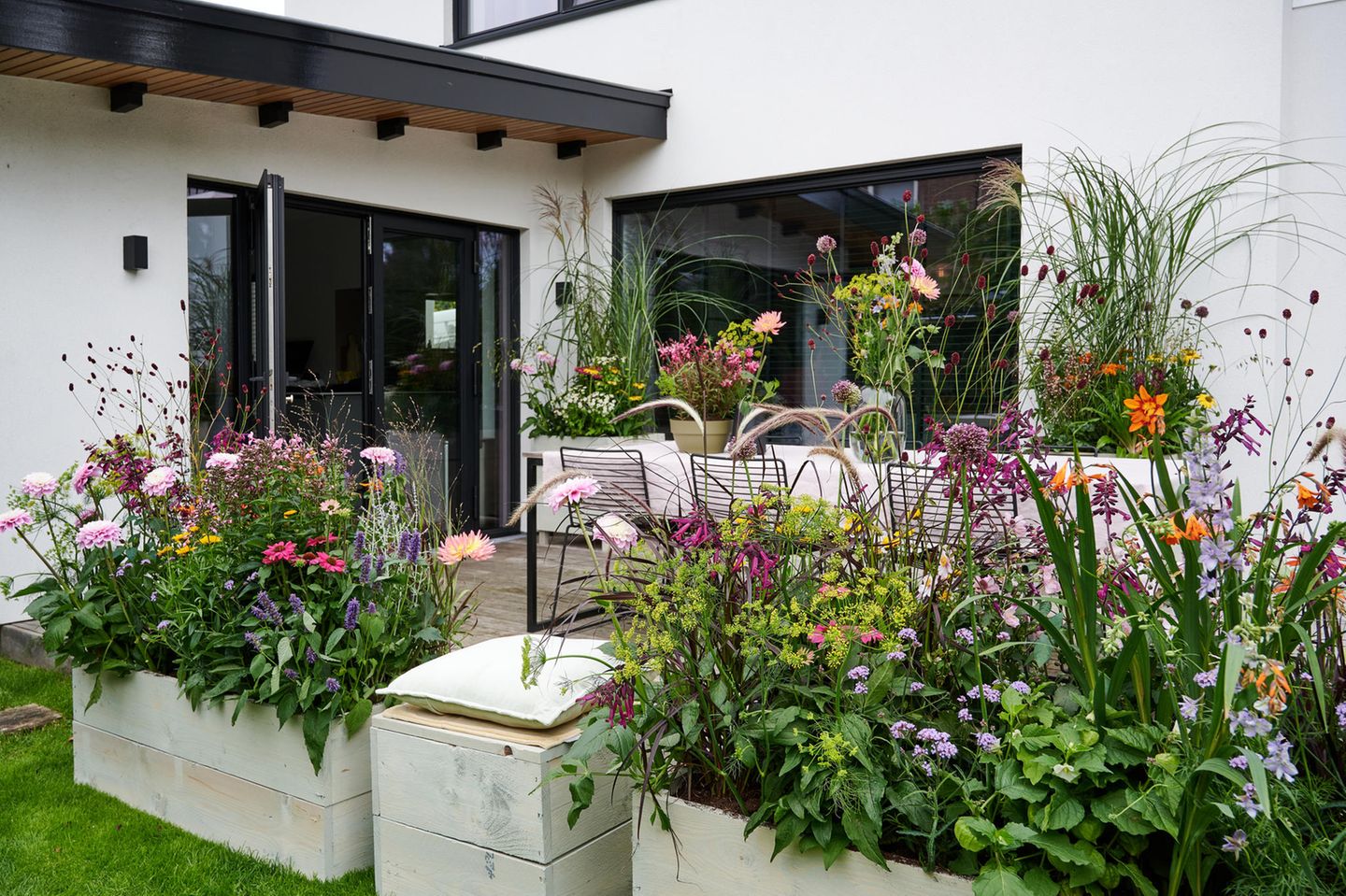 Üppig bepflanze Kästen mit Blumen auf einer Hinterhaus-Terrasse