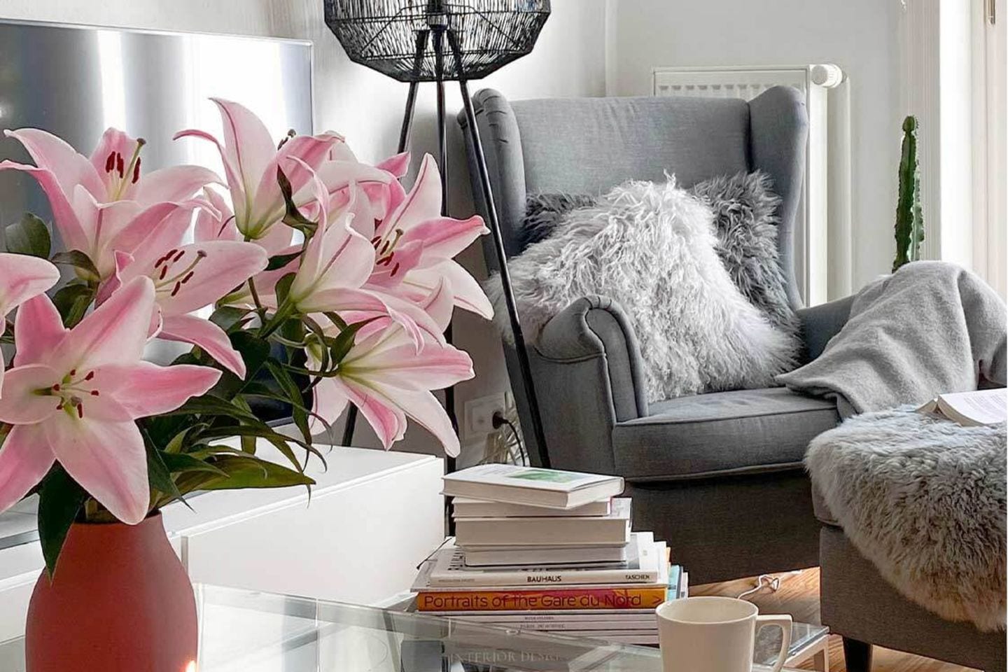 Cozy eingerichtetes Wohnzimmer mit dem Ohrensessel von Ikea, einer Stehleuchte, Lilien, Kerzen und vielem mehr