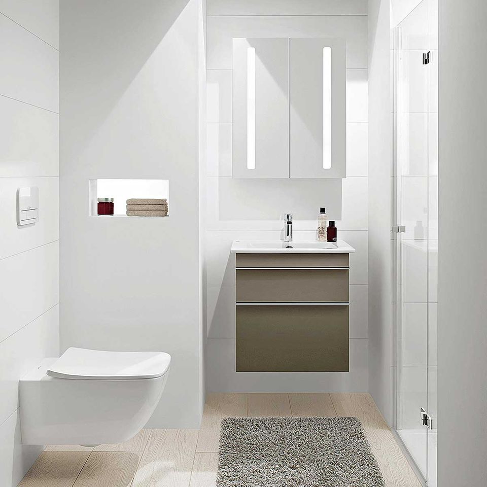 Kleines Bad in Weiß mit einem flauschigen Teppich und einem Waschtischunterschrank in Beige-Grau