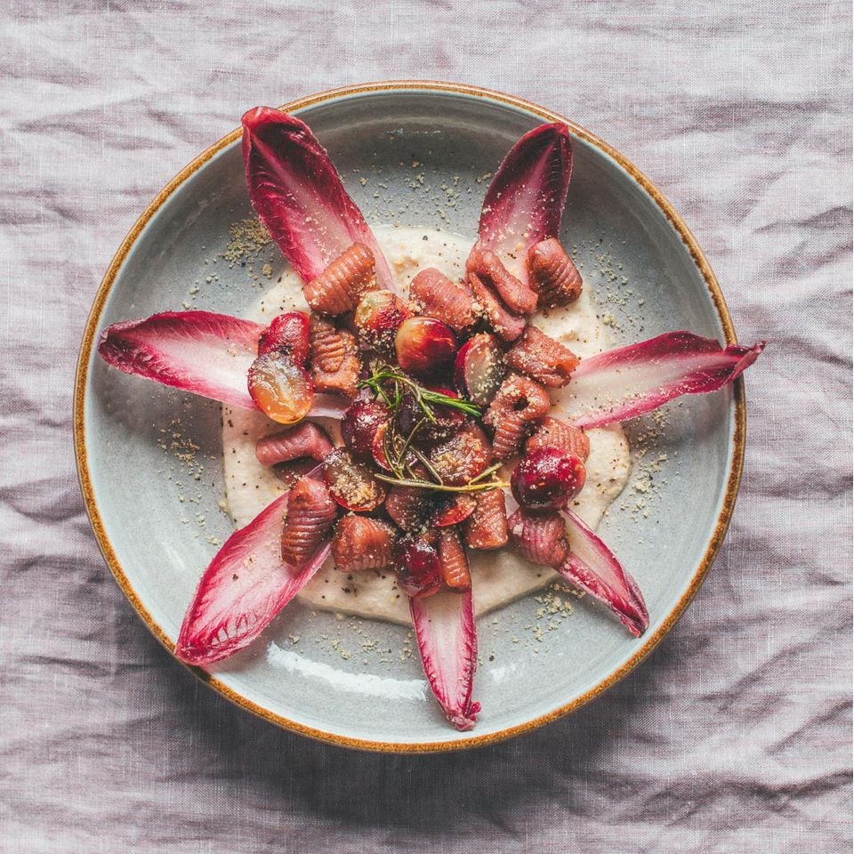 Rote Gnocchi liegen mit Salat und roten Trauben auf einem Teller