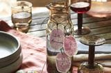Wasserkanne und Gläser auf einem Tisch mit Tischdecke und Geschenkanhängern in Pflaumenform