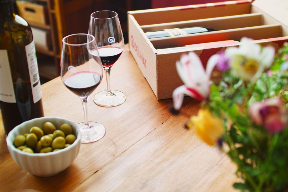 zwei Gläser mit Rotwein hinter einer Schale mit Oliven
